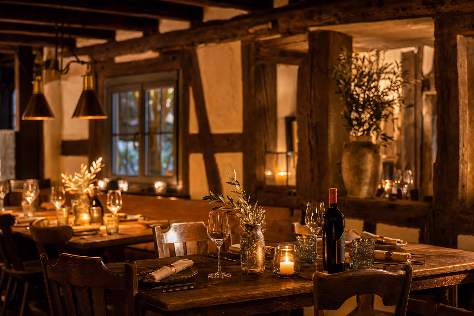 Warm beleuchtete Gaststube mit Fachwerk, gedeckten Holztischen und Kerzenlicht